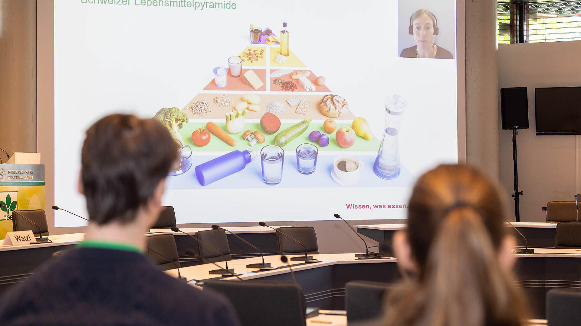 Zwei Personen schauen auf das Beamerbild auf dem die schweizerische Lebensmittel-Pyramide abgebildet ist.